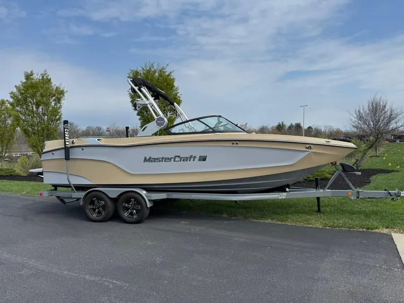 Slide: The Image of 2024 MasterCraft XT24 boat on trailer, parked outdoors on a sunny day. - 3