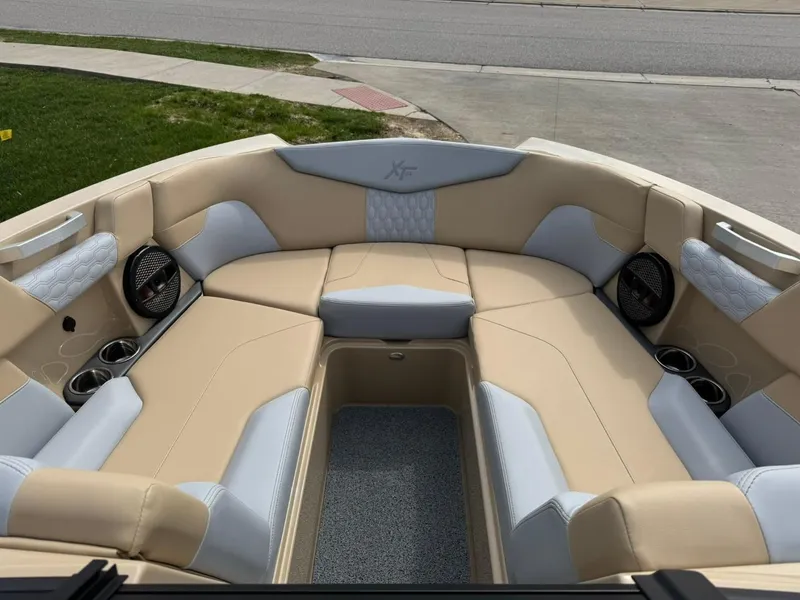 Slide: The Image of 2024 MasterCraft XT24 boat interior with beige and gray seating, cup holders, and speakers. - 9