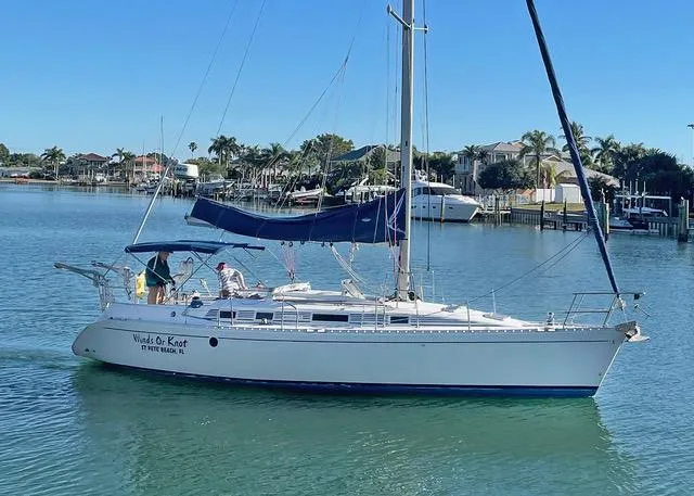 Slide: The Image of 1990 Beneteau Sloop sailing in a calm marina with palm trees. - 1
