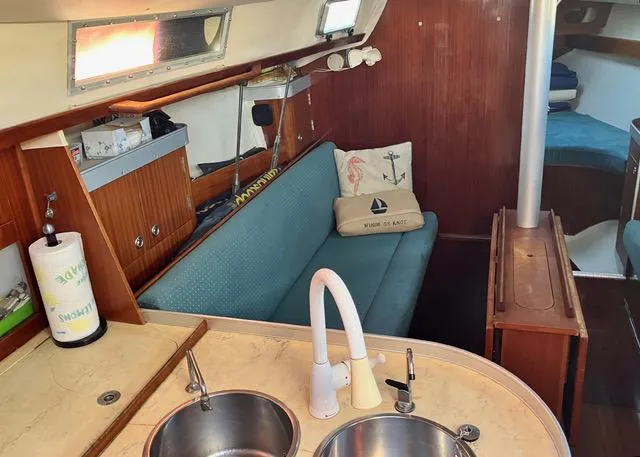 Slide: The Image of Interior of a 1990 Beneteau Sloop with cozy seating and kitchen area. - 10