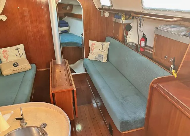 Slide: The Image of Interior of 1990 Beneteau Sloop with blue seating and wooden finishes. - 12
