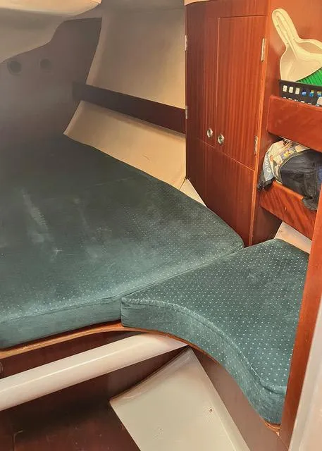 Slide: The Image of Cozy cabin interior of 1990 Beneteau Sloop with green cushions and wooden storage. - 13