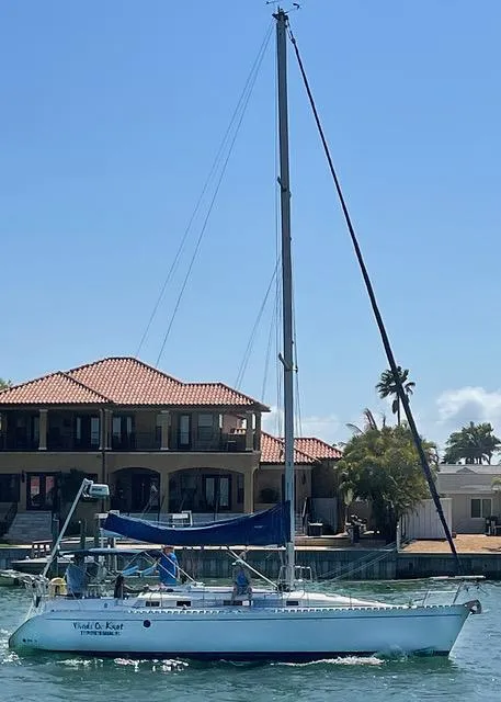 Slide: The Image of 1990 Beneteau Sloop sailing near waterfront homes under clear blue sky. - 2