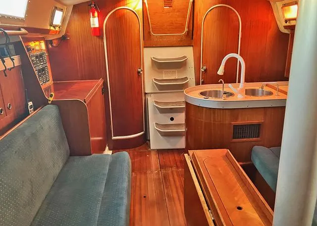 Slide: The Image of Interior of a 1990 Beneteau Sloop sailboat with wood finish and compact kitchen. - 8