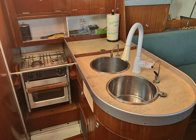 Slide: The Image of 1990 Beneteau Sloop kitchen with dual sinks, stove, and wooden cabinetry. - 9