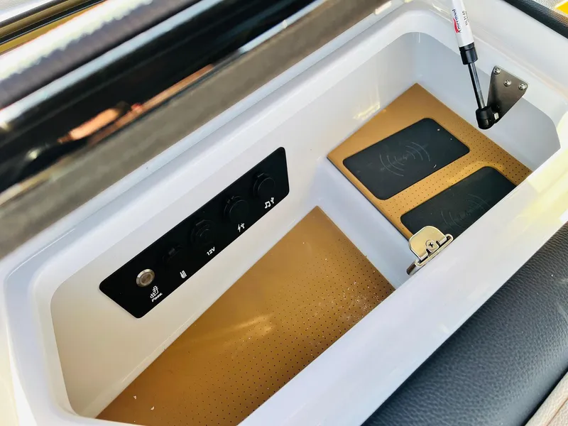 Slide: The Image of 2025 Nautique Super Air Nautique G25 Paragon storage compartment with control panel and wireless charging pads. - 36