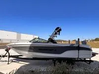 Slide: The Image of 2024 MasterCraft XT25 boat on trailer under clear blue sky. - 3