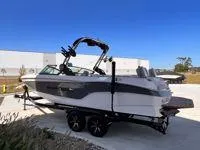 Slide: The Image of 2024 MasterCraft XT25 boat on trailer, parked outdoors under clear blue sky. - 5