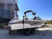 Slide: The Image of 2024 MasterCraft XT25 boat on trailer, parked outdoors under clear blue sky. - 6