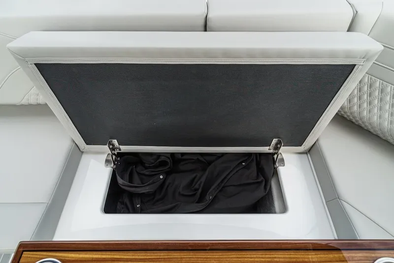 Slide: The Image of 2024 Cruisers Yachts 38 GLS OB storage compartment with open lid and black fabric inside. - 32