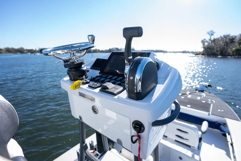 Slide: The Image of 2022 Young Boats 24 console on a sunny lake, showcasing steering and controls. - 22