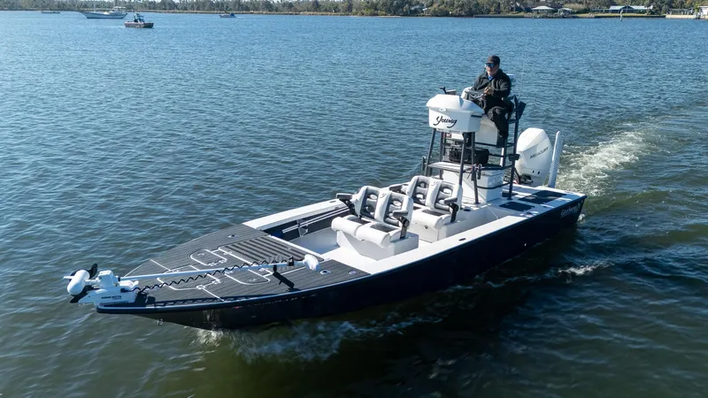 Slide: The Image of 2022 Young Boats 24 cruising on a calm lake with a person at the helm. - 30