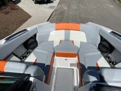 Slide: The Image of 2024 MasterCraft X22 boat interior with gray and orange seating, cup holders, and speakers. - 15