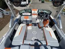 Slide: The Image of 2024 MasterCraft X22 boat interior with orange and gray seating, advanced dashboard, and spacious layout. - 16