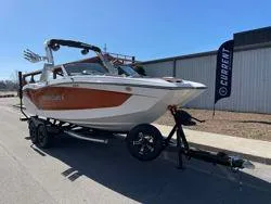 Slide: The Image of 2024 MasterCraft X22 boat on trailer, parked outdoors, showcasing sleek design and vibrant colors. - 2