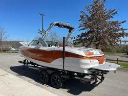 Slide: The Image of 2024 MasterCraft X22 boat with orange and white design on a trailer. - 4