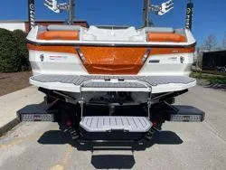 Slide: The Image of 2024 MasterCraft X22 boat with orange accents, rear view in outdoor setting. - 7