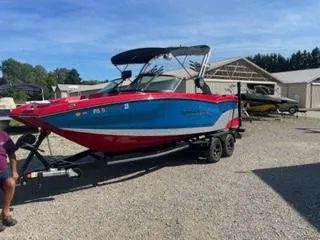 Slide: The Image of 2023 MasterCraft NXT 22 boat with red and blue design on a trailer. - 2