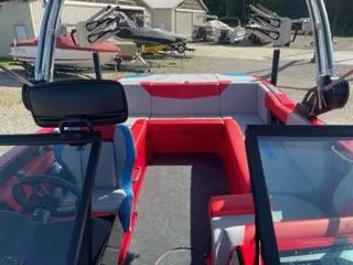 Slide: The Image of 2023 MasterCraft NXT 22 boat interior with red and gray seating, docked outdoors. - 9