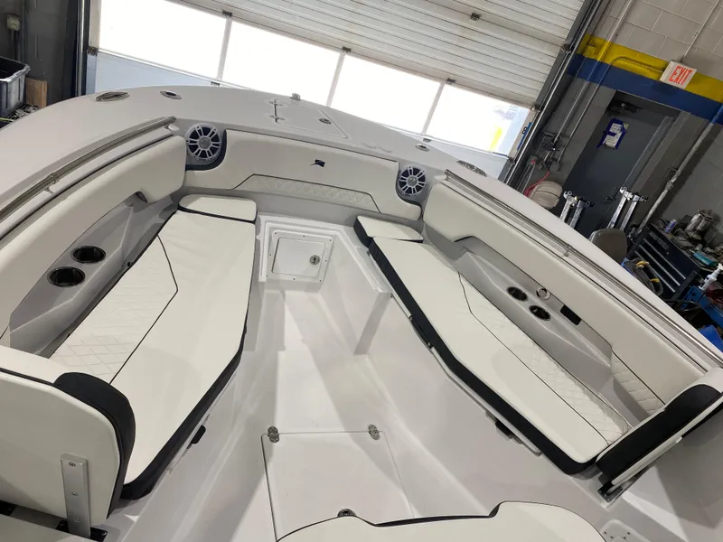 Slide: The Image of 2025 Stingray 253CC boat interior with white seating and cup holders in a garage. - 13
