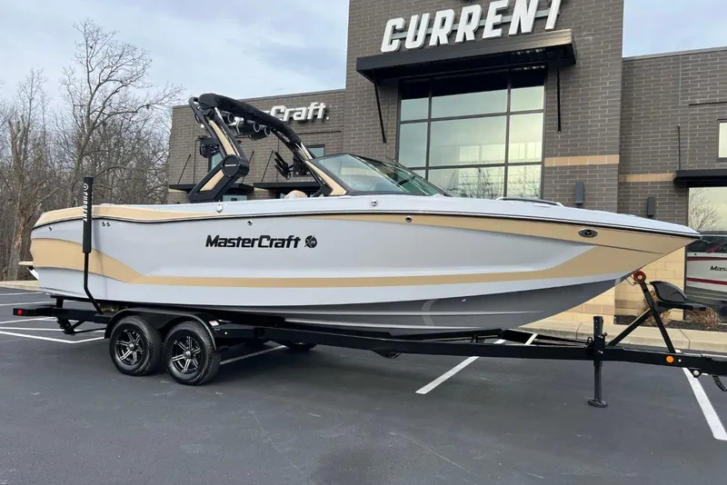 The Image of 2024 MasterCraft X26 boat on trailer, parked outside a building. - 0