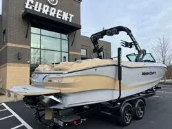 Slide: The Image of 2024 MasterCraft X26 boat on trailer in parking lot, overcast sky. - 2