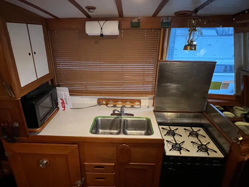 Slide: The Image of 1972 Grand Banks 42 Classic kitchen with stove, sink, and wooden cabinetry. - 10