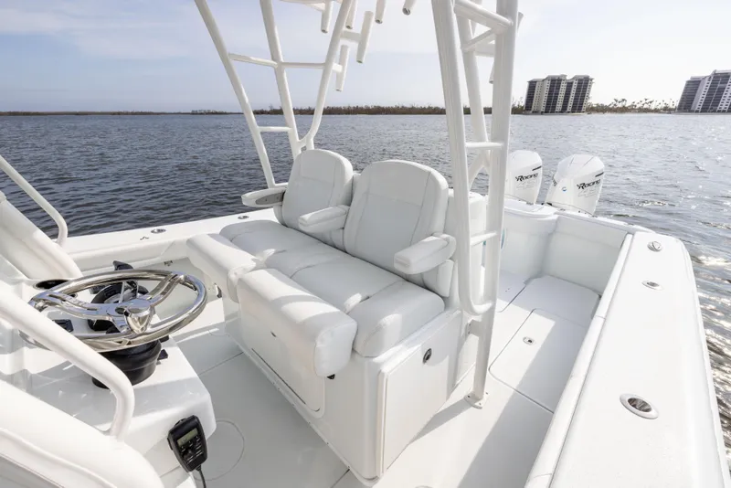 Slide: The Image of 2021 Yellowfin 36 Offshore boat interior with white seating and steering wheel, on calm water. - 32