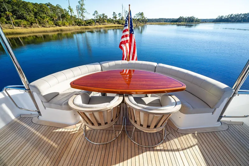 Slide: The Image of 2016 Hatteras M60 yacht deck with seating, overlooking serene water and clear skies. - 10
