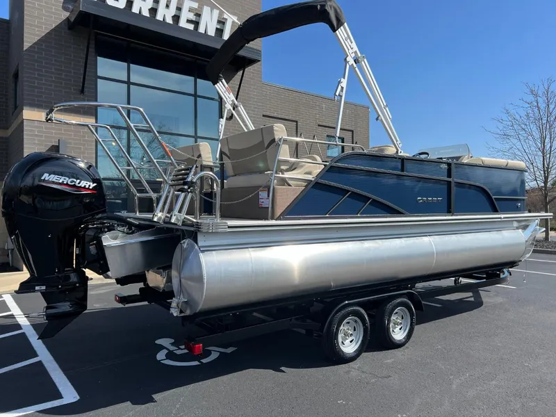 Slide: The Image of 2024 Crest Classic LX 220 pontoon boat on trailer, parked outside a building. - 3