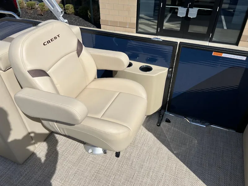 Slide: The Image of 2024 Crest Classic LX 220 boat seat with beige upholstery and cup holders. - 9