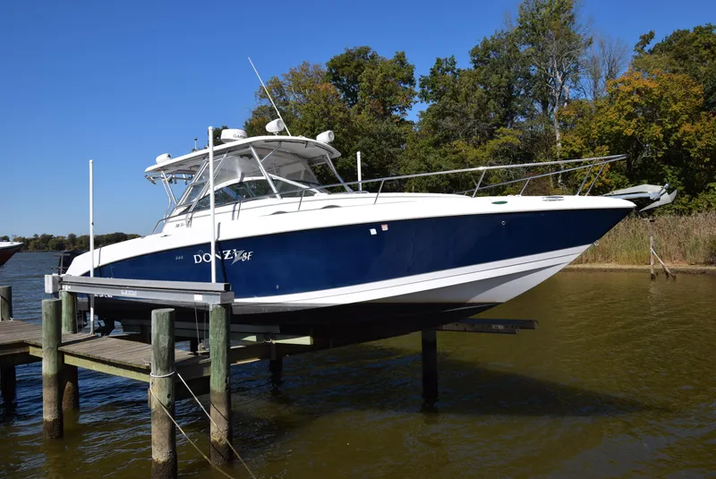 The Image of 2005 Donzi 38 ZSF boat docked on a lift by a lake with trees in the background. - 0