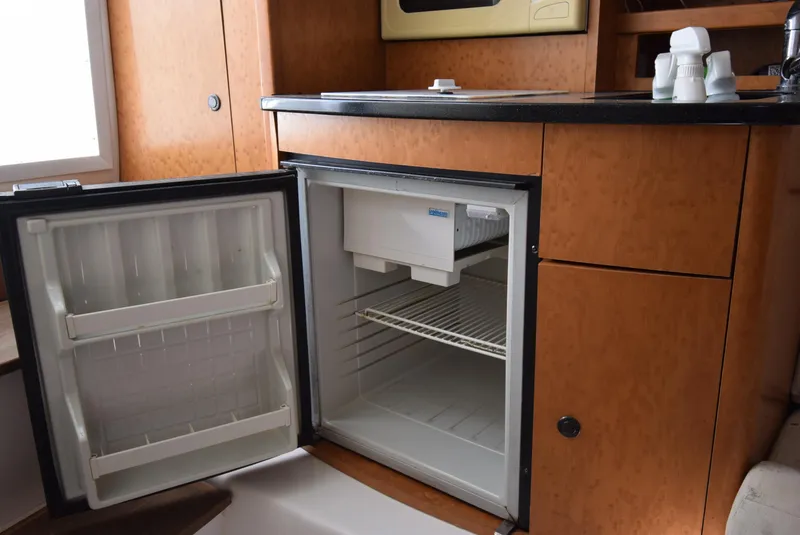 Slide: The Image of Open mini fridge in 2005 Donzi 38 ZSF boat interior, showcasing wooden cabinetry. - 40