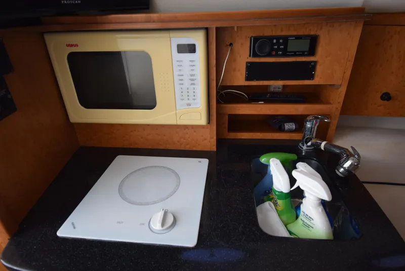 Slide: The Image of 2005 Donzi 38 ZSF boat kitchen with microwave, stove, sink, and cleaning supplies. - 41