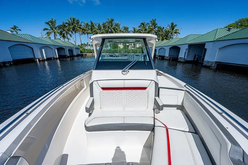 Slide: The Image of 2021 Tiara Yachts 34 LS boat docked near boathouses, clear sky, and palm trees. - 17