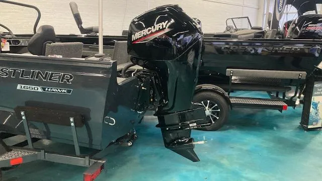Slide: The Image of 2025 Crestliner 1650 Hawk boat with Mercury outboard motor in showroom. - 2