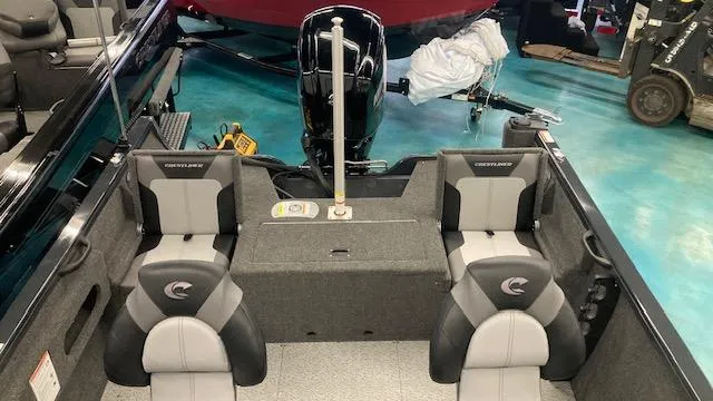 Slide: The Image of 2025 Crestliner 1650 Hawk boat interior with seating and motor, in showroom setting. - 3