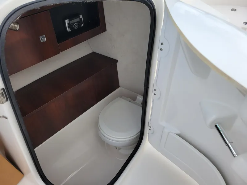 Slide: The Image of 2017 Robalo R227 Dual Console boat interior with compact marine toilet and storage. - 12