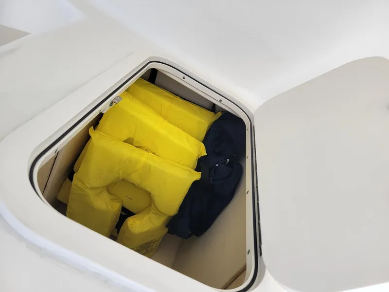 Slide: The Image of Storage compartment with yellow life jackets on a 2017 Robalo R227 Dual Console boat. - 13