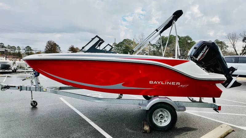 Slide: The Image of 2025 Bayliner M17 boat in vibrant red on a trailer, parked outdoors. - 2