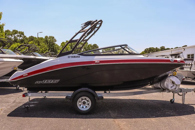 Slide: The Image of 2025 Yamaha Boats AR195 on trailer, sleek black and red design, parked outdoors. - 5