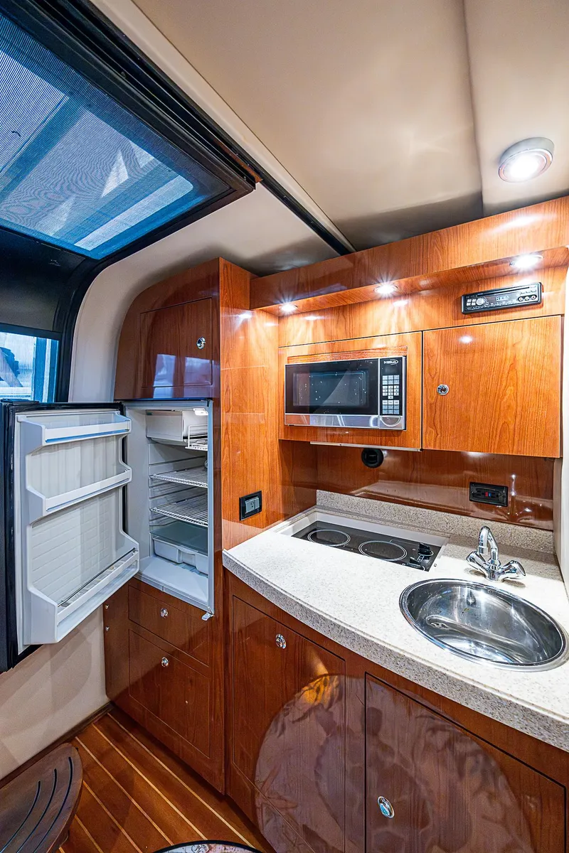 Slide: The Image of 2008 Regal Commodore 3760 IB yacht kitchen with fridge, microwave, sink, and wooden cabinetry. - 38
