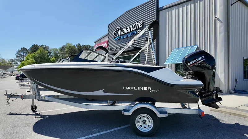 The Image of 2025 Bayliner M17 boat on trailer outside dealership, featuring sleek design and Mercury outboard motor. - 0