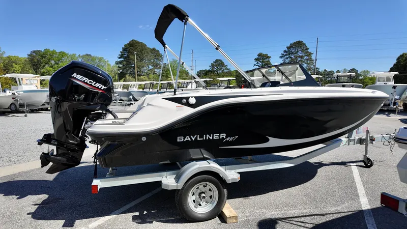 Slide: The Image of 2025 Bayliner M17 boat on trailer with Mercury outboard motor, parked outdoors. - 2