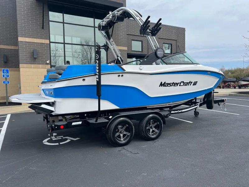 Slide: The Image of 2024 MasterCraft XT20 boat in blue and white, parked on a trailer. - 3