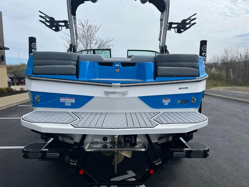 Slide: The Image of 2024 MasterCraft XT20 boat, rear view, blue and white design, parked outdoors. - 4