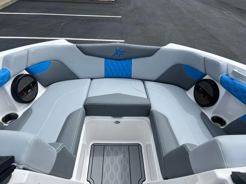 Slide: The Image of 2024 MasterCraft XT20 boat interior with gray and blue seating, speakers, and cup holders. - 8