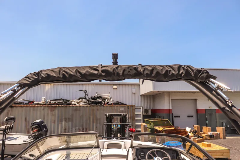 Slide: The Image of 2025 Yamaha Boats AR195 with wakeboard tower, parked outdoors under clear blue sky. - 16