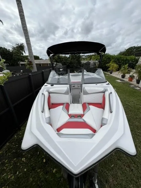 Slide: The Image of 2015 Tigé RZR boat with red and white interior, parked outdoors. - 4