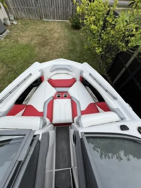 Slide: The Image of 2015 Tigé RZR boat with red and white seating, parked on grass. - 5